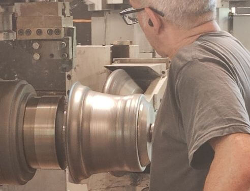 man at a cnc machine performing metal spinning metal forming